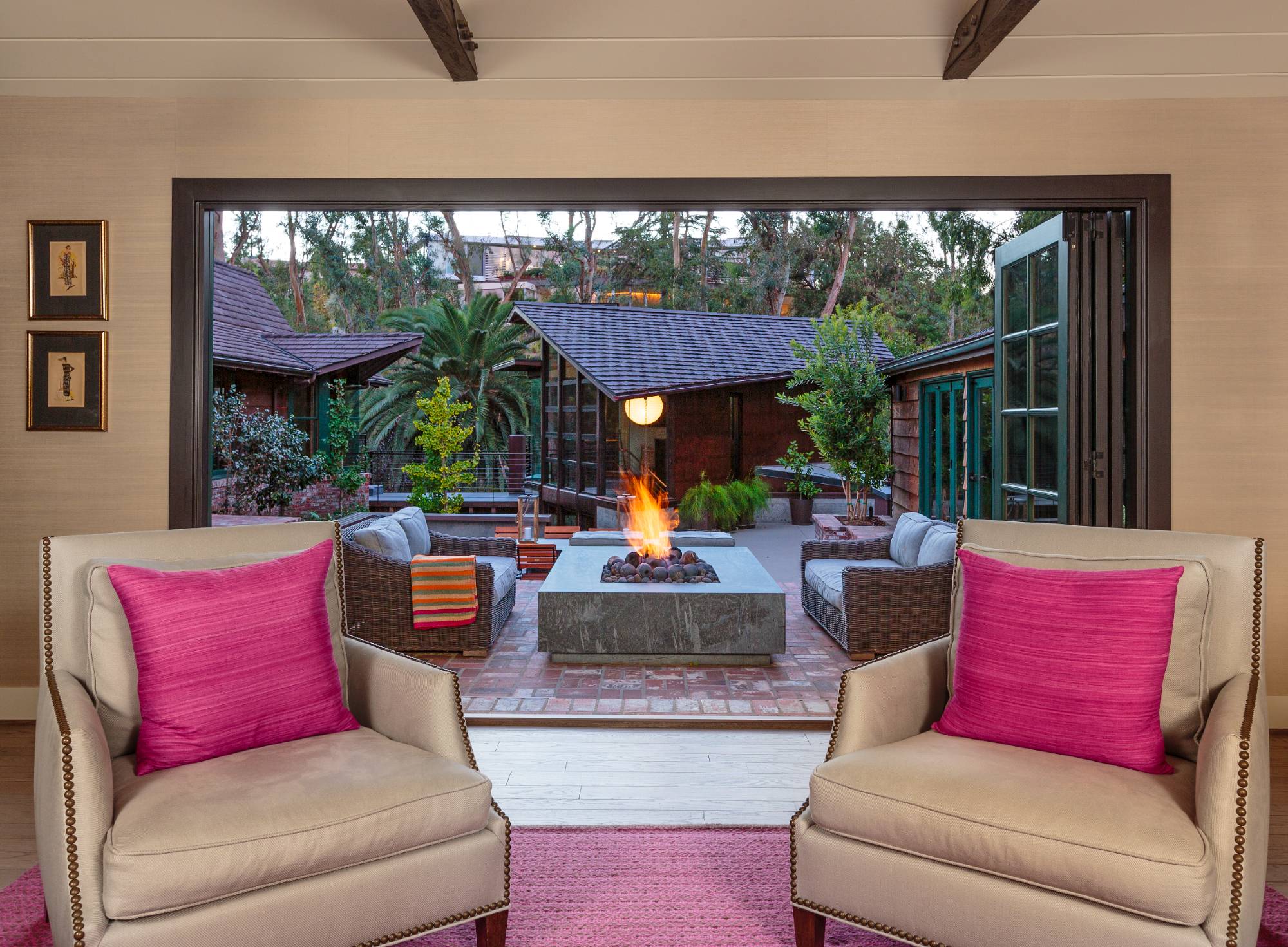 Brentwood interior, living room looking out to courtyard with fire pit, beige nailhead-trim chairs, indoor-outdoor flow.
