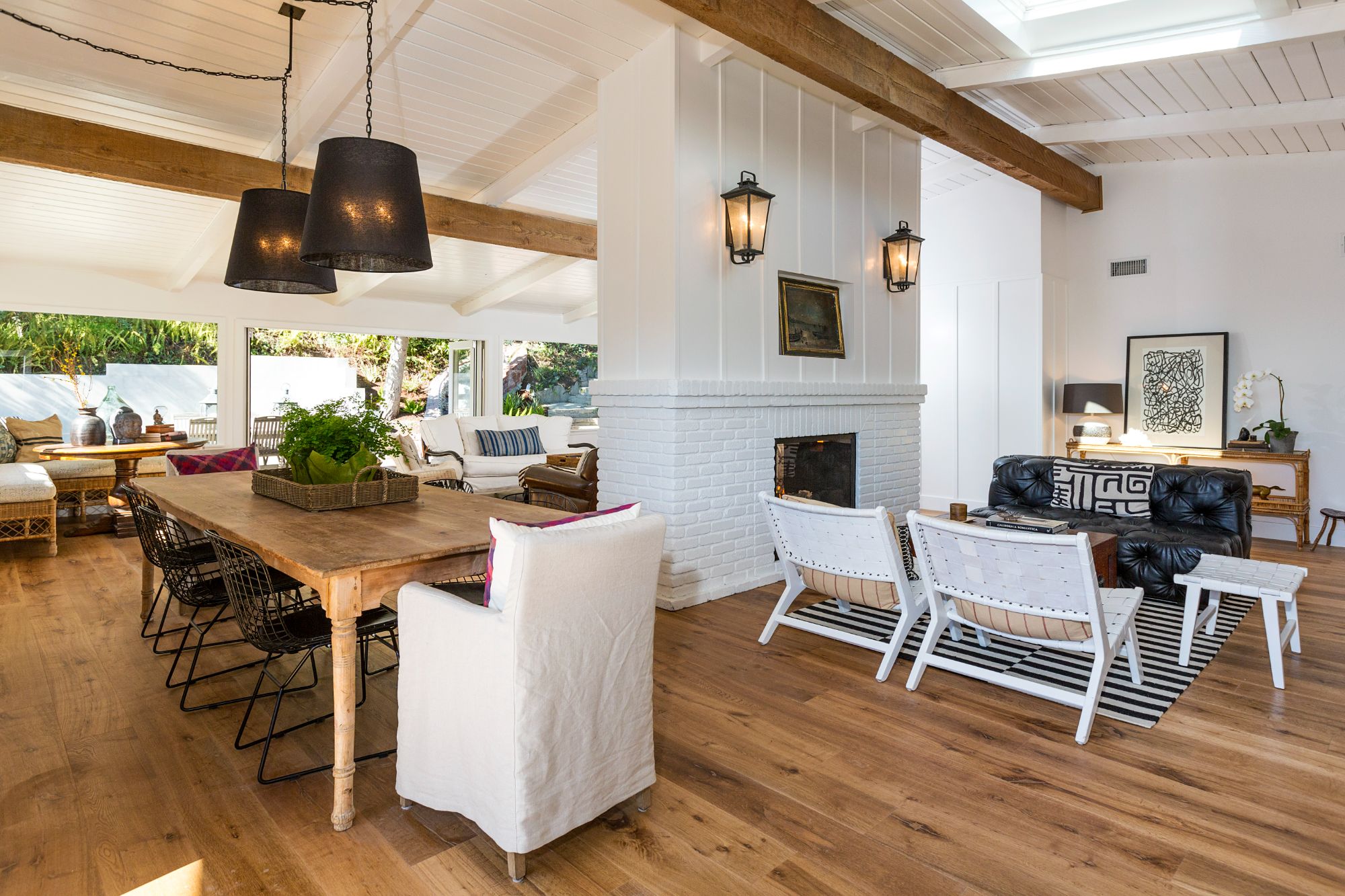 Pacific Palisades beach house, dining and reading area with the reverse side of the double-sided fireplace, exposed beams, drum pendants, sliders to outdoor patio. ESRL Development.